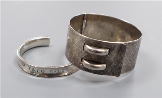 A Tiffany 925 cuff bangle and an engraved white metal hinged belt style bangle.